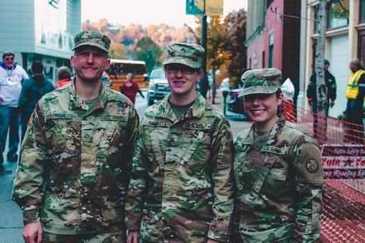 Three US Army soldiers in camouflage uniform smiling at a public event in Wheeling, WV.